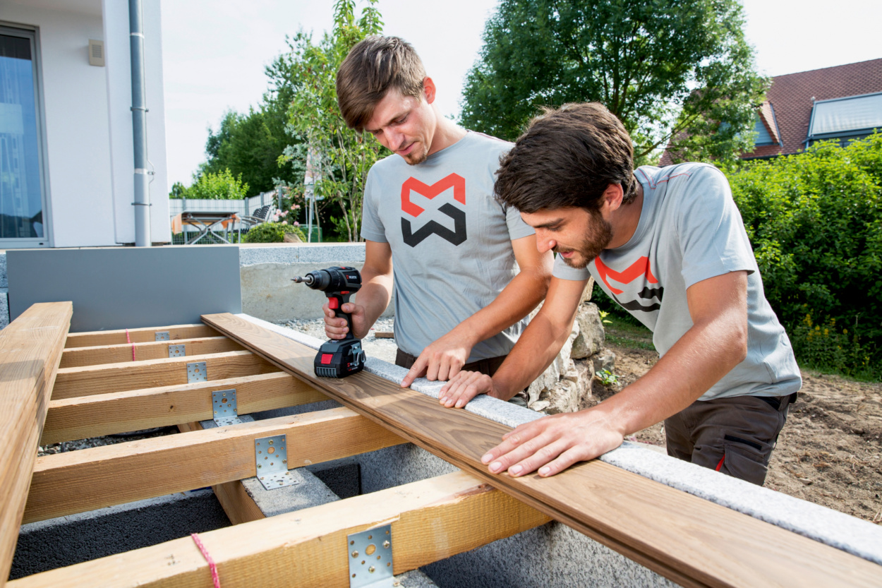 Zwei Männer bauen eine Terrasse aus Holz mit einem Würth Akkuschrauber Zwei Männer bauen eine Terrasse aus Holz mit einem Würth Akkuschrauber