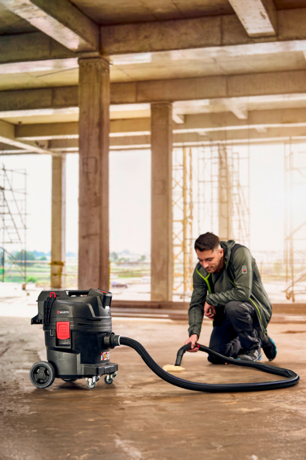 Mann auf Baustelle mit Staubsauger